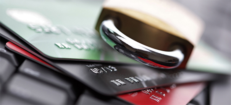 Three credit cards on a keyboard with a metal lock on top of them.
