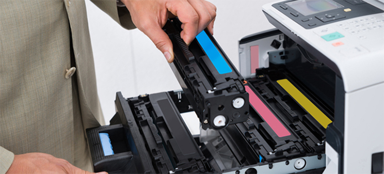 Man holding a cartridge and hovering it on top of a printer.