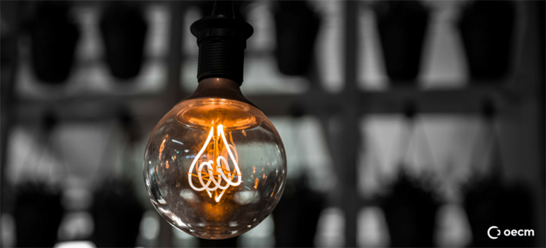 A transparent lightbulb that is lit up with an amber colour.
