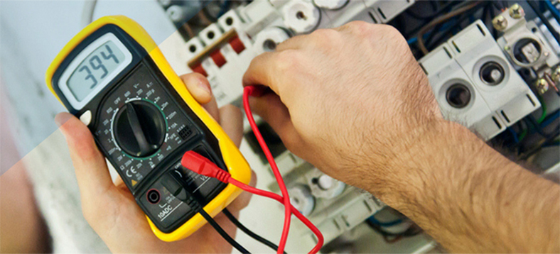 Male hands using a voltmeter on a machine.