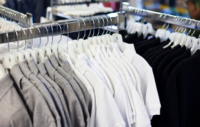 two clothing racks with many grey. white and black polo shirts