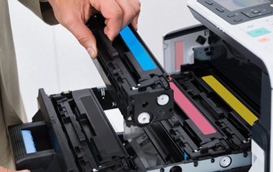 a person loading a blue ink cartridge into a printer