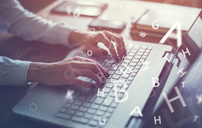 person typing on laptop keyboard and letters are flying off the keyboard