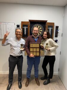 OECM's top three winners of the Darts Tournament pose for a picture-2 men-1 woman-holding trophies and plaque