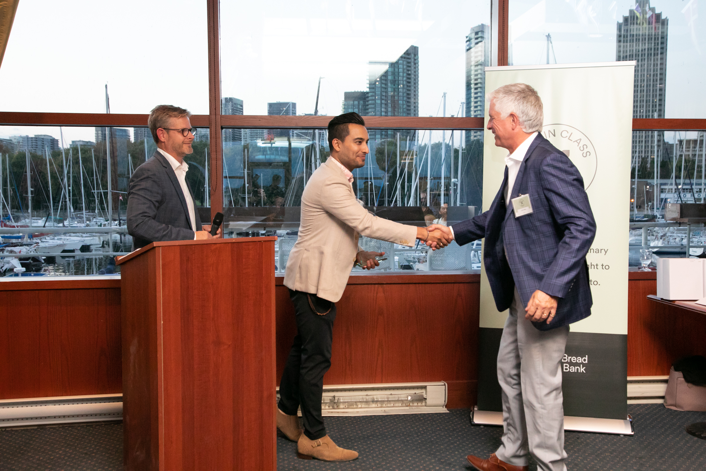 President and CEO, John Sabo (far right) accepts the 2023 Workplace Champion award on behalf of OECM, from event emcee, Gurdeep Ahluwalia, from CHFI 98.1 and Neil Hetherington, CEO of Daily Bread Food Bank.