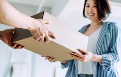 person handing a parcel in a box to a woman