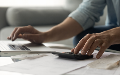 person using a calculator and laptop on a table