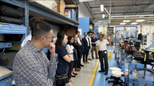 Felipe Arias shows OECM staff Global Furniture Group’s testing lab, highlighting 28 years of rigorous quality control for durable products.