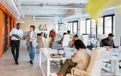 people in an office space sitting in cushioned work chairs and elongated tables