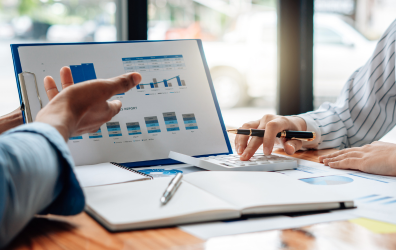 Two people around a laptop looking at data through graphs on screen.