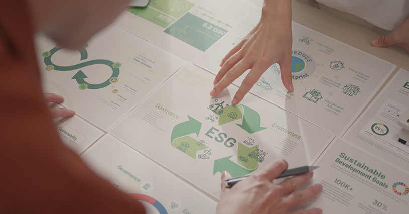 A group of young professionals examines an ESG-focused presentation, strategizing on sustainable business practices and green technologies to enhance environmental responsibility.