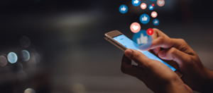 hands clicking on device screen with social hearts, thumbs up floating out of the screen