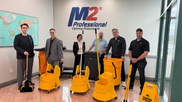 OECM and M2 representatives standing with cleaning tools during a facility visit