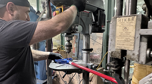 Worker operating a machine to assemble or drill cleaning tool components on the production floor
