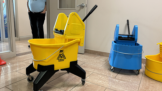 M2’s newer ergonomic bucket and wringer, with the traditional blue and yellow buckets in the back