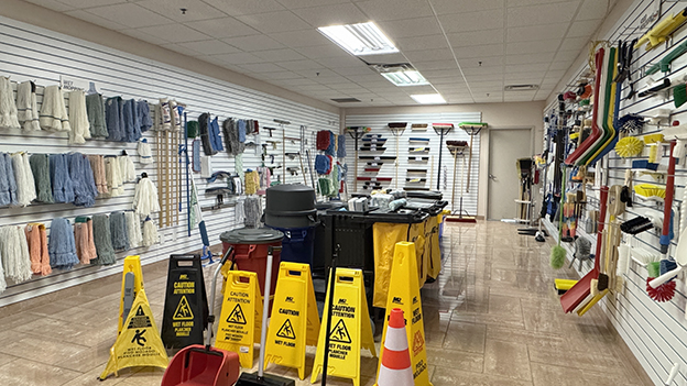 Showroom wall displaying a range of mops, cleaning tools, and safety signage products