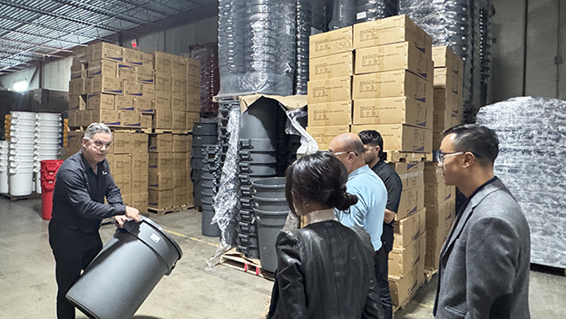 Michael showing OECM staff the durability of their grey garbage bins