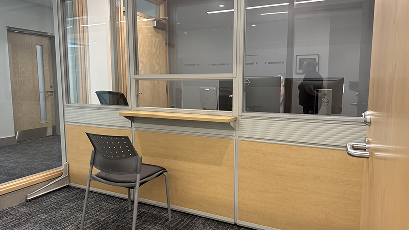Customer-service workspace with a glass barrier, sliding interaction window and writing surface.